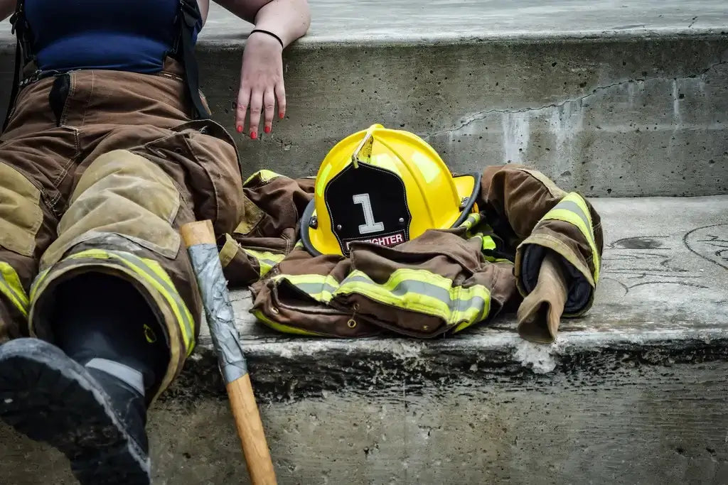 Vrouw zittend in brandweerpak naast haar helm